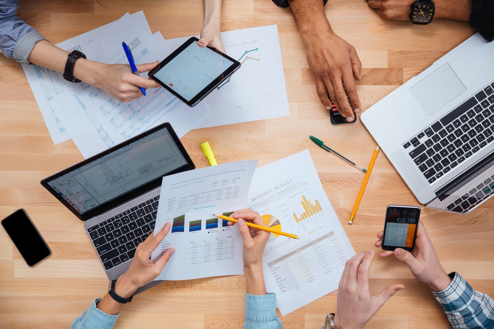 Group of people working with laptops, tablet and smartphones together and making financial report-1