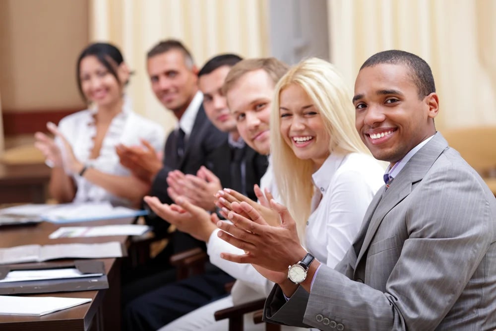 Multi ethnic business group greets you with clapping and smiling