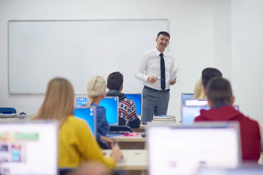 group of students with teacher in computer lab classrom learrning lessons,  get help and support-1